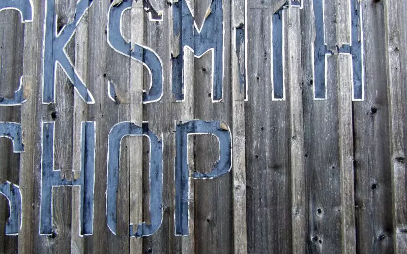 A weathered hand-painted shop sign on wooden boards