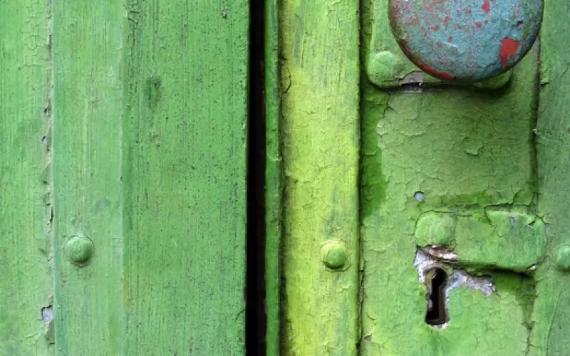 A simple latch on a weathered green door