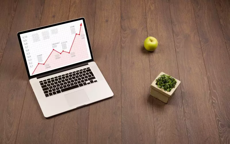 A laptop showing a chart on a wooden desk