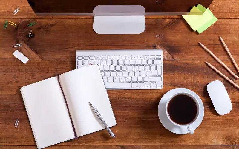 An overhead writing desk with a notebook and coffee