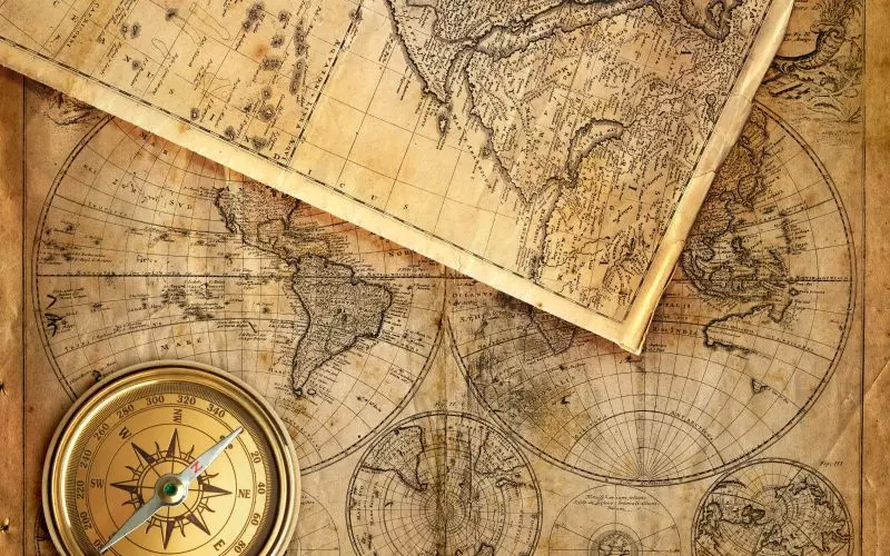 An antique map with a brass compass resting on it