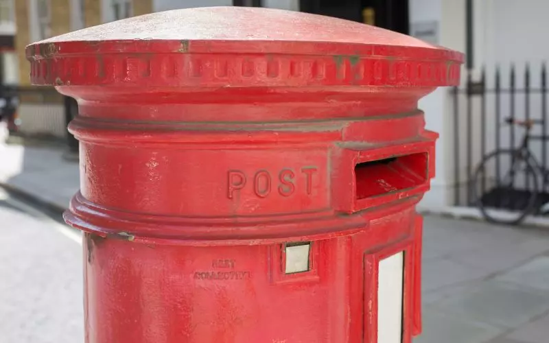 A red pillar postbox on a street