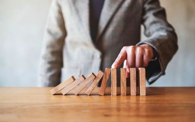 A hand stopping a falling row of dominoes