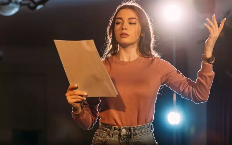 A woman holding a script under stage lights