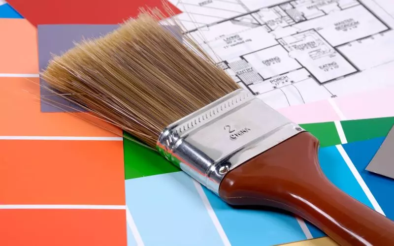 Paint brushes beside color chips and plans