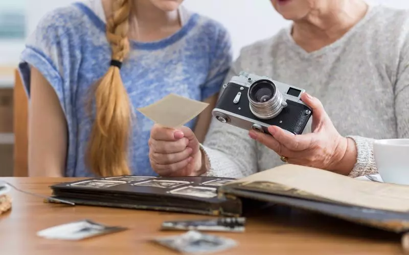 Two people sorting photographs into an album