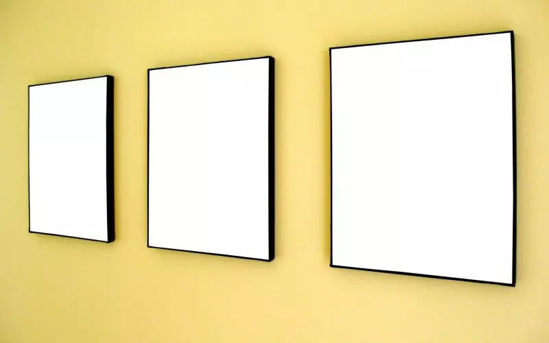 Three empty frames grouped on a yellow wall