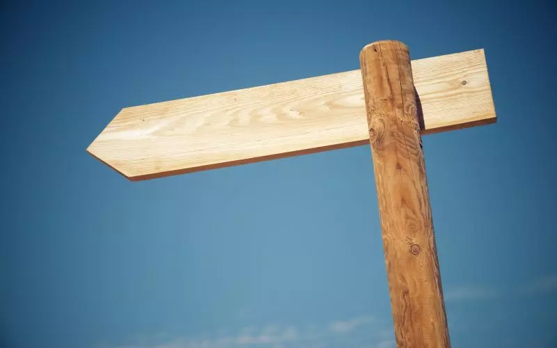 A wooden signpost with two arms against the sky