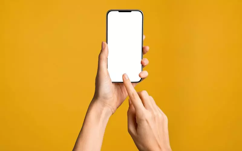Hands holding a phone against a yellow ground