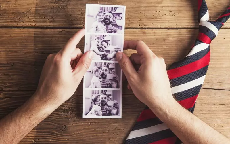 Hands sorting photographs on a wooden table