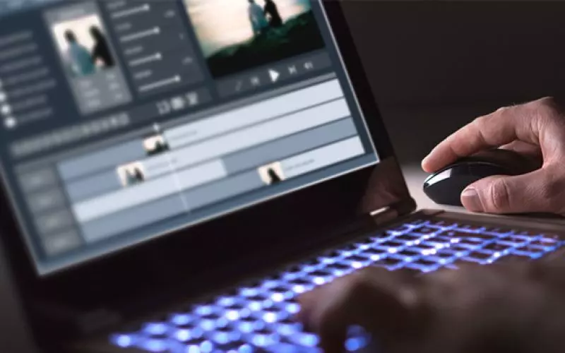Hands at a keyboard below a video editing timeline
