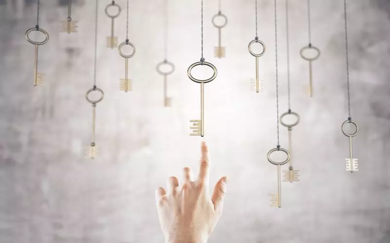 A hand reaching for one of many keys hanging on strings