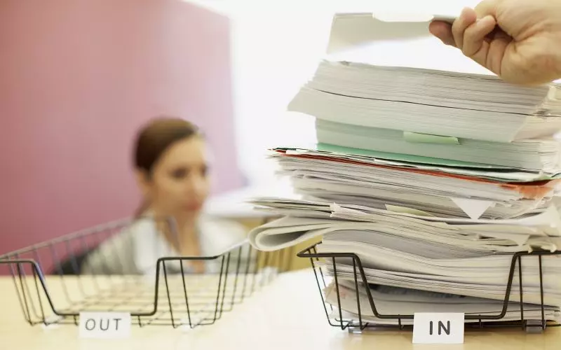 Paperwork piled in an in tray on an office desk