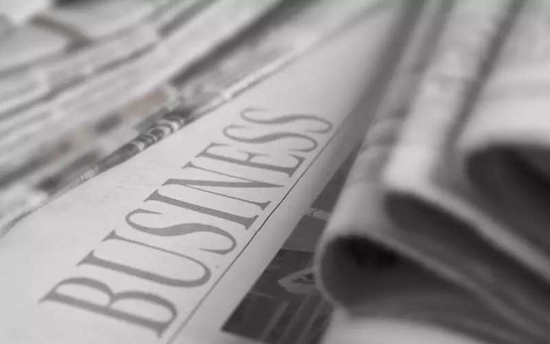 A stack of folded newspapers, the business section on top