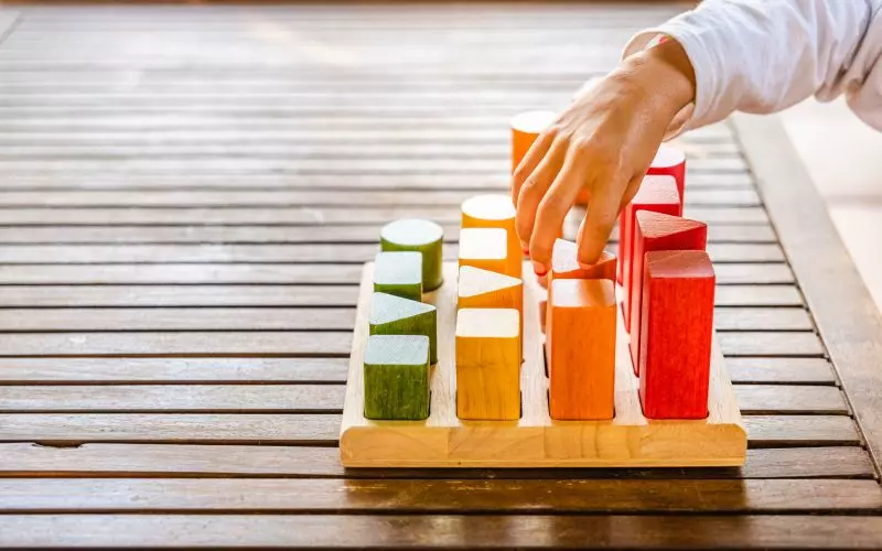 A hand arranging colored blocks into a row