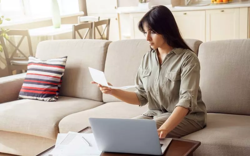 Someone looking at a laptop on a sofa at home