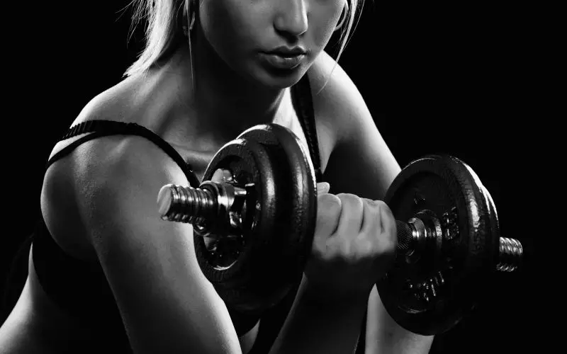 A woman lifting a dumbbell in a black and white photo