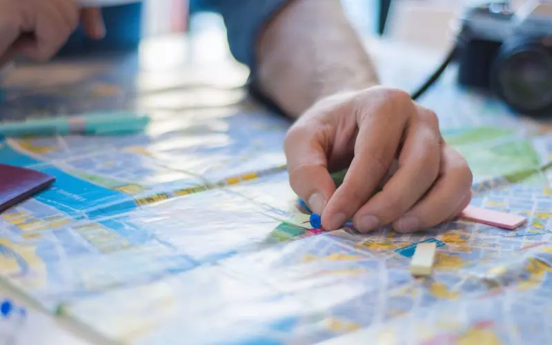 Hands marking a route on a printed road map