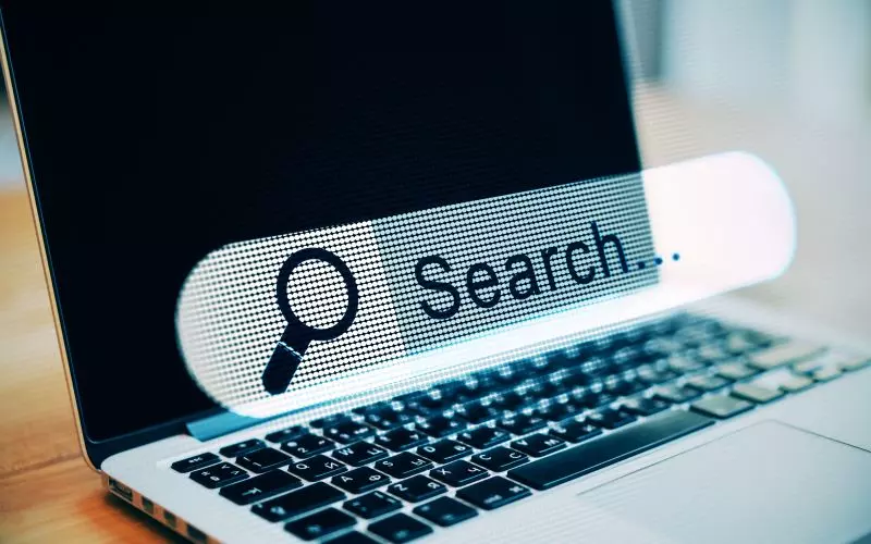 A laptop showing a search bar and a magnifier