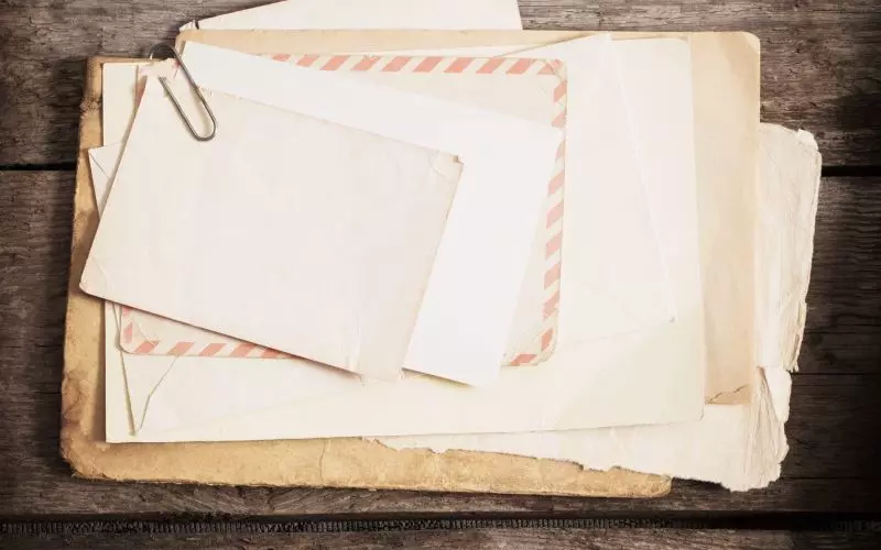 A stack of aged envelopes on wood