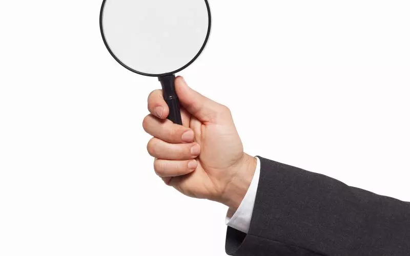 A hand holding a magnifying glass