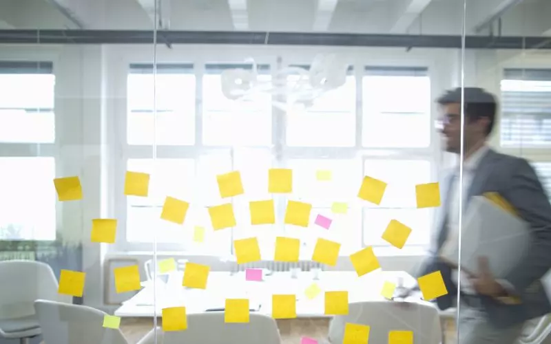 A glass office wall covered in sticky notes