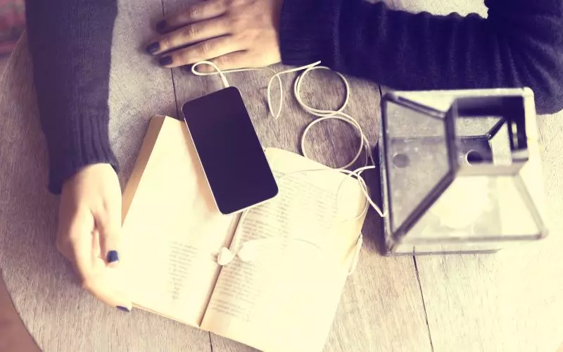 Earbuds and a phone laid out on a wooden desk