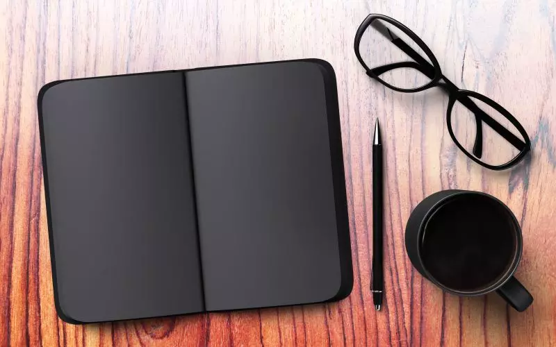 An open portfolio on a desk with glasses and a pen