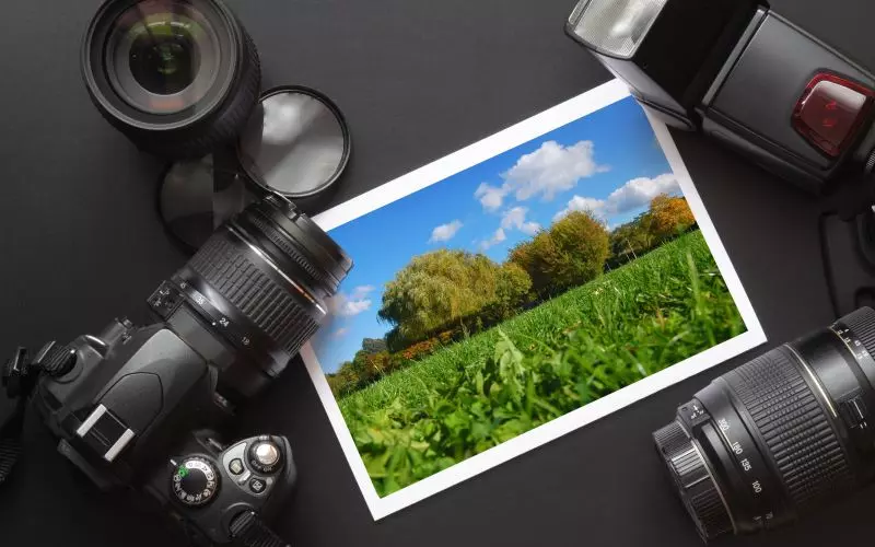 Two cameras and lenses beside a printed landscape photograph