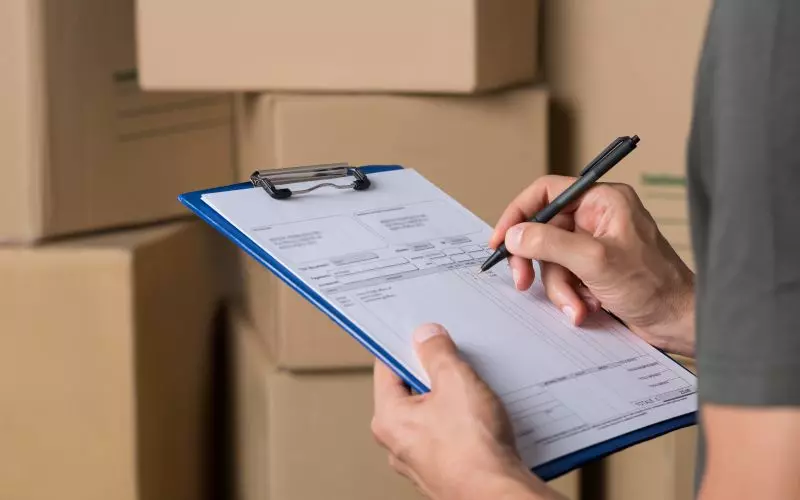 Hands filling in a form on a clipboard