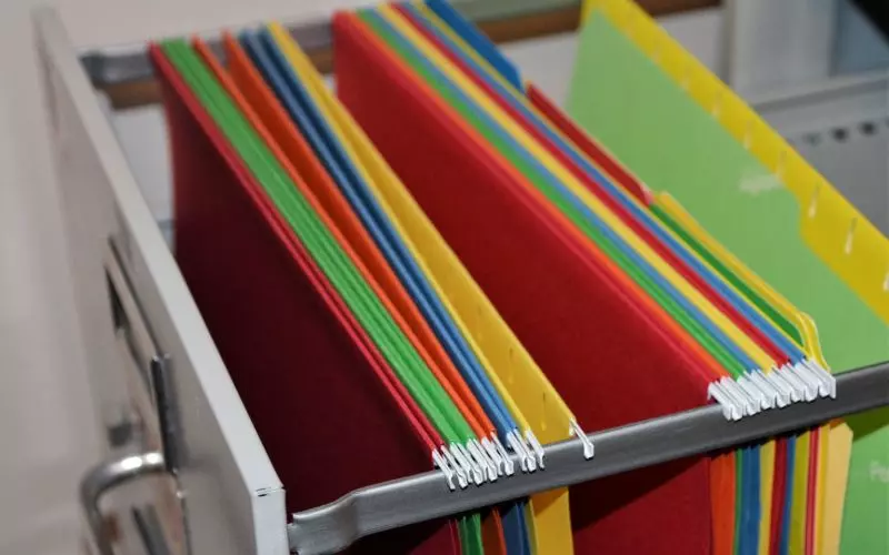An open file drawer of colored hanging folders