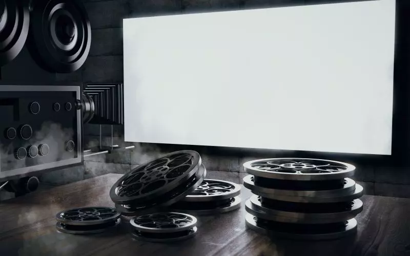 A projector and film reels in front of a blank screen