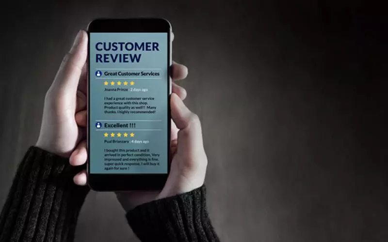 A hand holding a phone showing a five star customer review