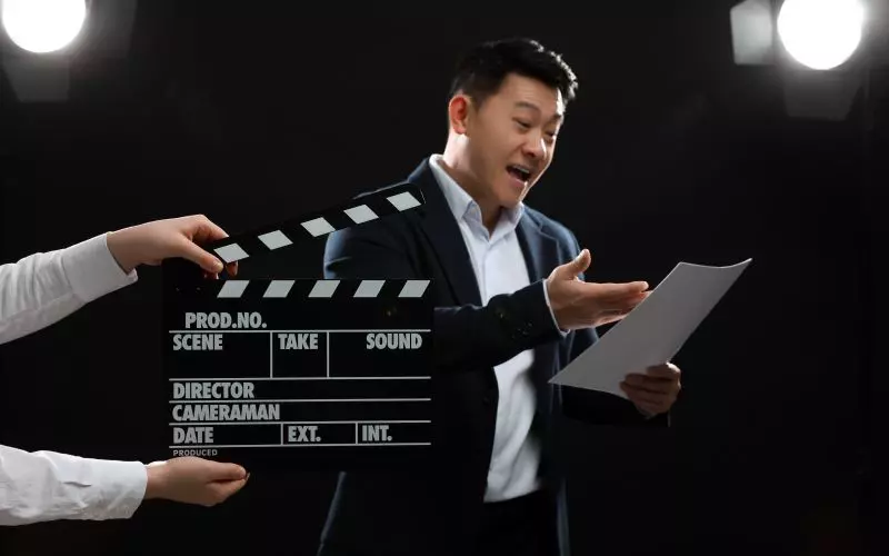 A man with a script beside a film clapperboard