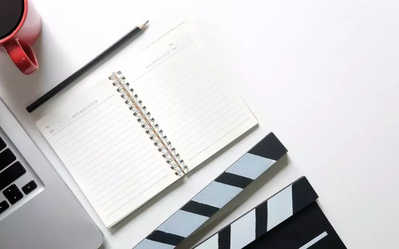 A blank notebook and a clapperboard on a desk