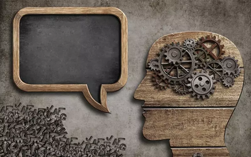 A head made of cogs beside a wooden speech bubble