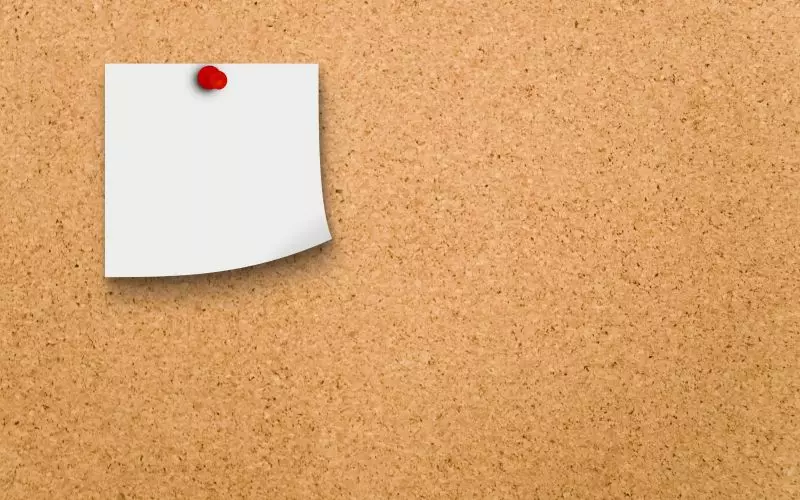 A single blank note pinned to a cork board