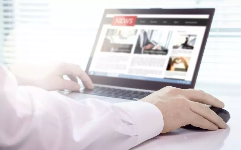 Hands on a laptop showing a news website