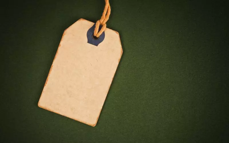 A blank kraft label tag on a dark green surface