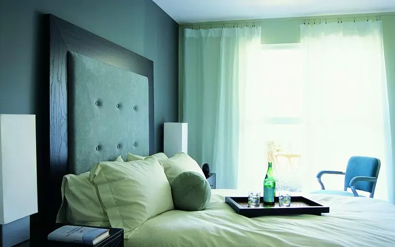 A quiet, sunlit bedroom with a neatly made bed