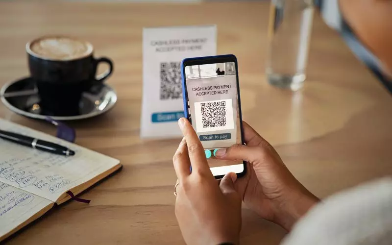 A phone scanning a QR code beside a coffee