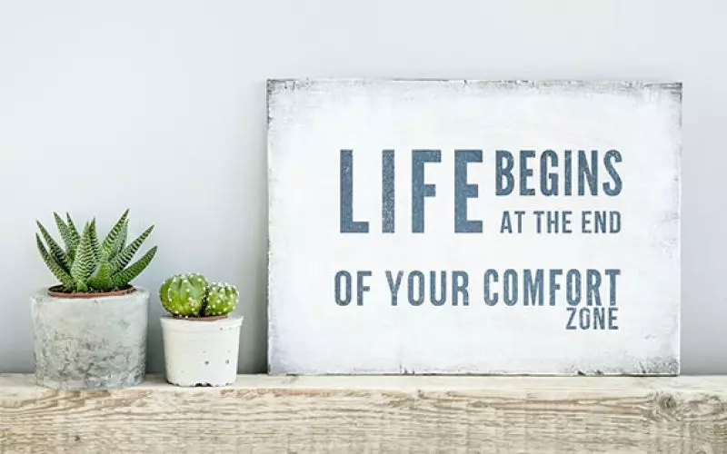 A framed print reading life begins at the end of your comfort zone