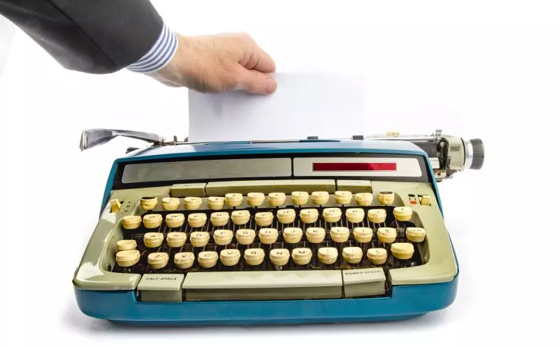 A hand feeding paper into a typewriter